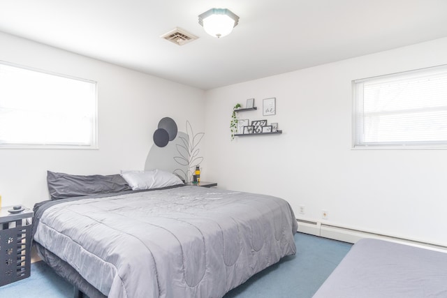 bedroom with a baseboard heating unit, carpet, and visible vents