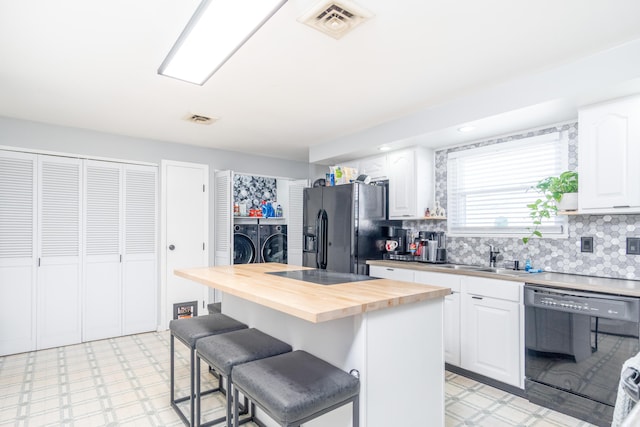 kitchen with a sink, black appliances, light floors, and butcher block counters