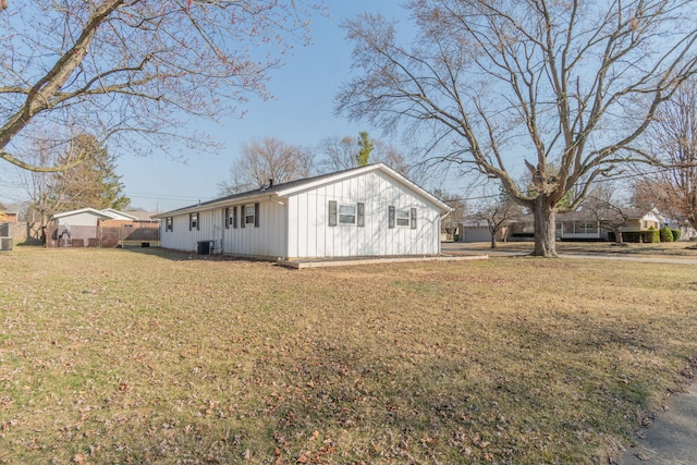 view of side of home featuring cooling unit, a lawn, and board and batten siding