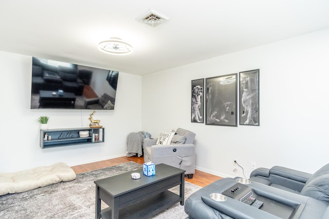 living room featuring visible vents, baseboards, and wood finished floors