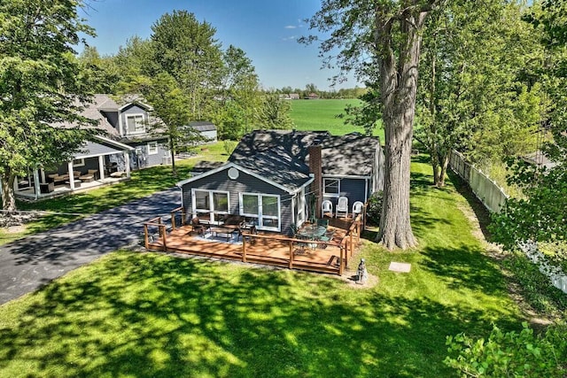 back of property featuring fence, a deck, and a yard