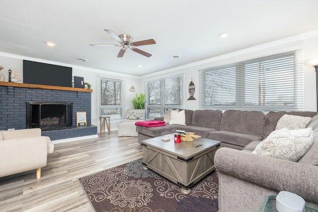 living area with a fireplace, recessed lighting, ornamental molding, a ceiling fan, and light wood-type flooring