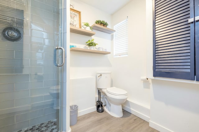 bathroom with toilet, baseboards, wood finished floors, and a shower with shower door