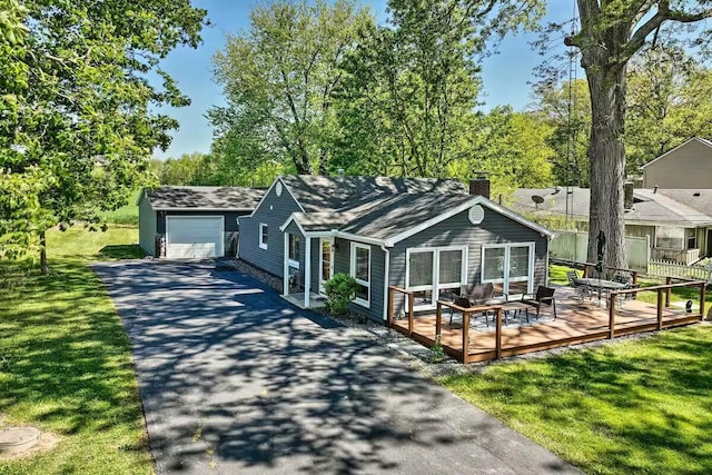 view of front facade with driveway, a chimney, a front lawn, and a deck