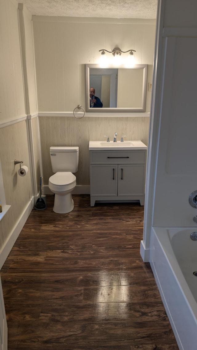 bathroom featuring vanity, hardwood / wood-style flooring, toilet, and a textured ceiling