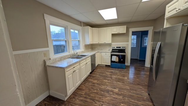 kitchen with sink, appliances with stainless steel finishes, dark hardwood / wood-style floors, white cabinets, and a drop ceiling