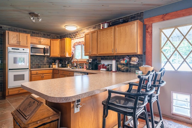 302 N W St, Arcanum, OH 45304 - kitchen featuring stainless steel microwave, white double oven, backsplash, a peninsula, and light countertops