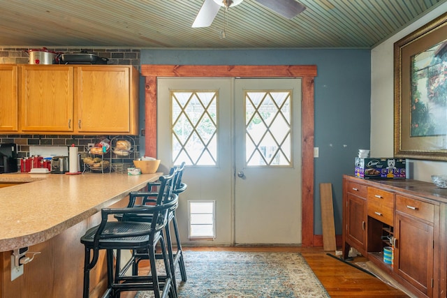 302 N W St, Arcanum, OH 45304 - kitchen featuring wood finished floors, a kitchen breakfast bar, ceiling fan, brown cabinets, and decorative backsplash