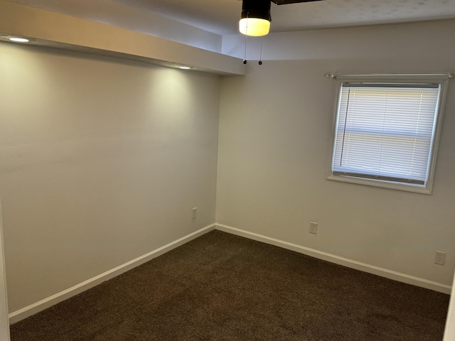 unfurnished room featuring dark colored carpet and baseboards