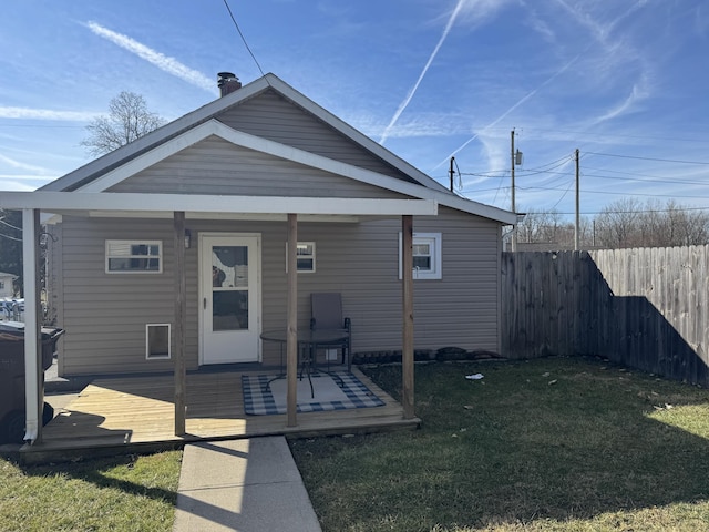 rear view of property with fence and a lawn