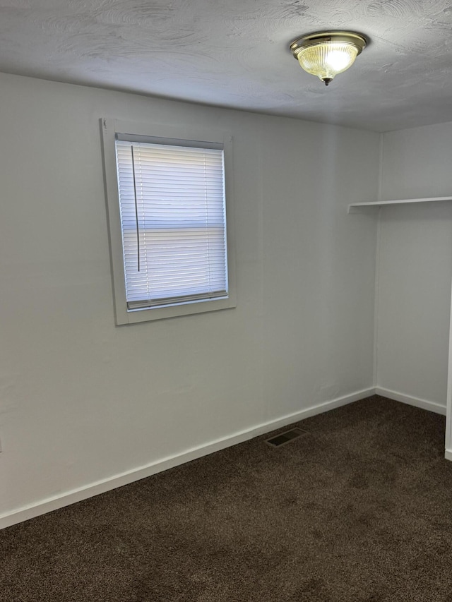 carpeted spare room with visible vents, baseboards, and a textured ceiling