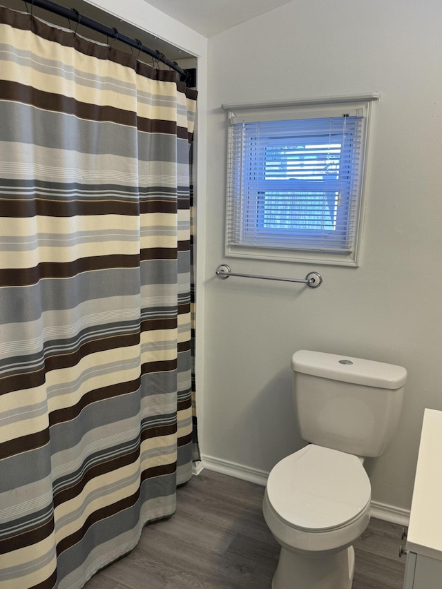 bathroom with toilet, baseboards, wood finished floors, and a shower with shower curtain