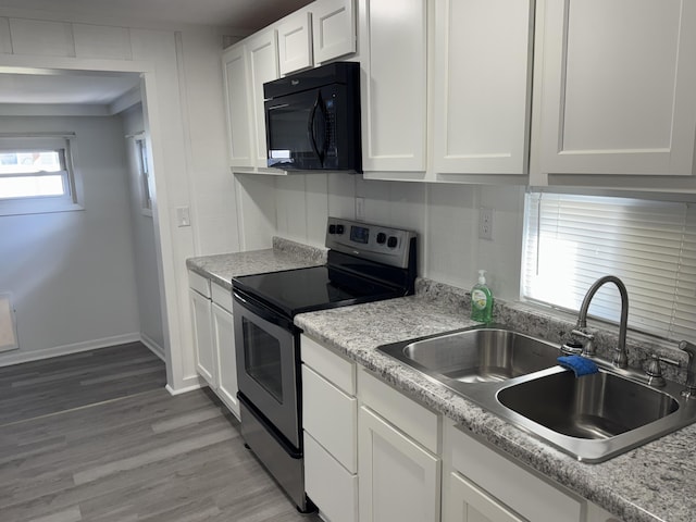 kitchen with black microwave, a sink, white cabinetry, stainless steel range with electric cooktop, and light wood-type flooring