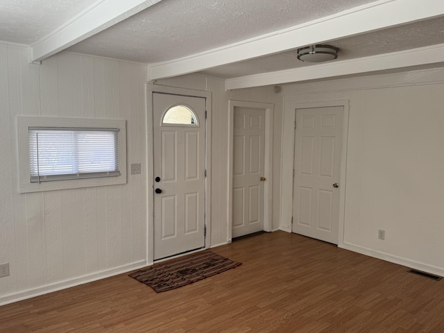 entrance foyer with beam ceiling, visible vents, a textured ceiling, wood finished floors, and baseboards