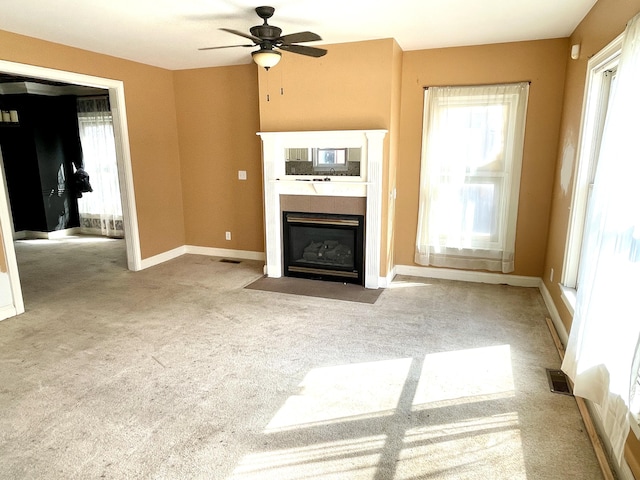 unfurnished living room with a fireplace with flush hearth, a ceiling fan, visible vents, and carpet floors