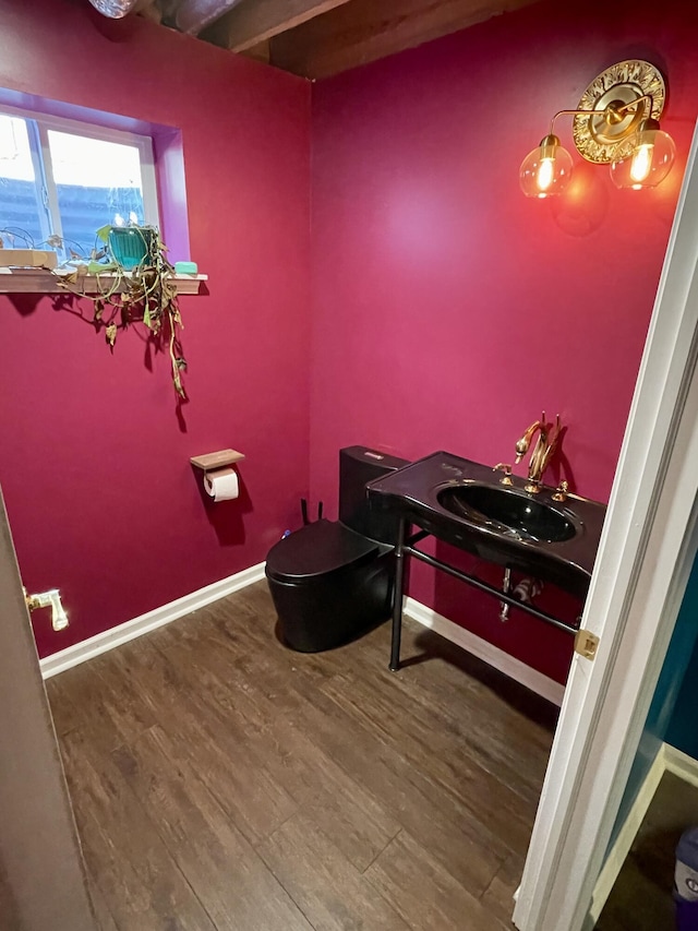 half bath featuring toilet, vanity, baseboards, and wood finished floors