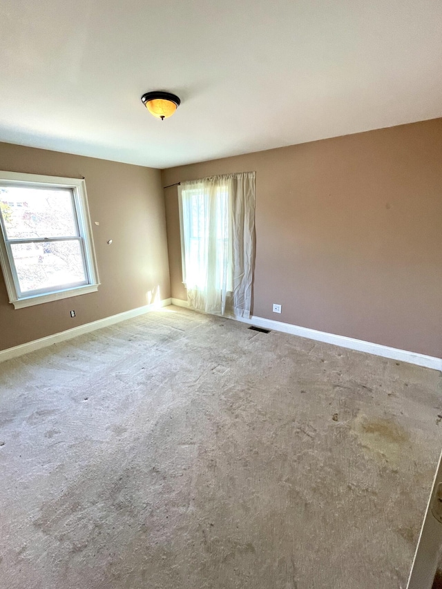 carpeted empty room featuring visible vents and baseboards