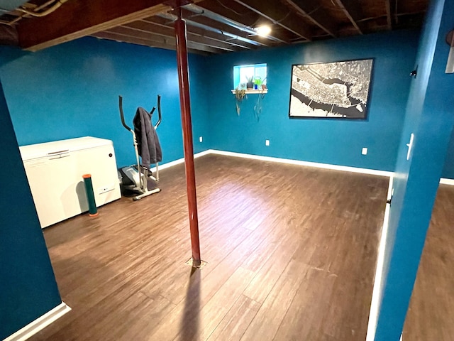 below grade area featuring fridge, baseboards, and wood finished floors