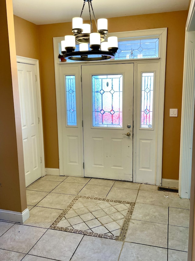 foyer entrance featuring light tile patterned floors, baseboards, and an inviting chandelier