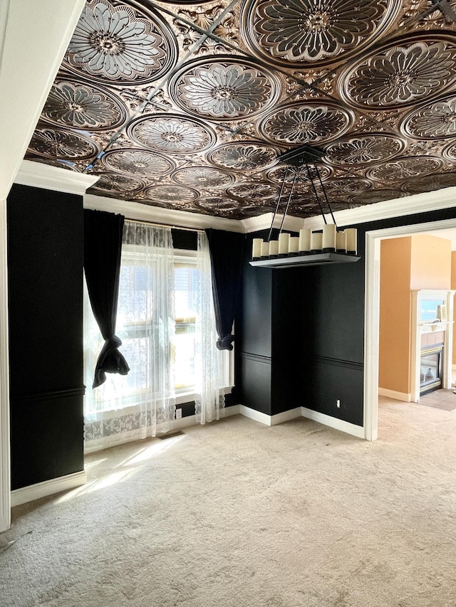 carpeted spare room featuring crown molding, baseboards, and an ornate ceiling