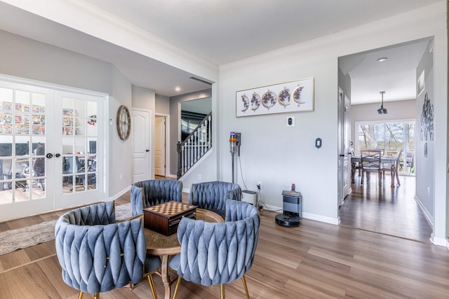 living area with wood finished floors, french doors, baseboards, and stairs
