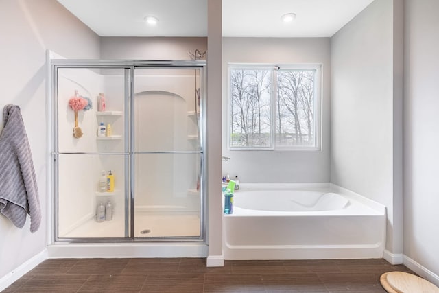 full bathroom with a garden tub, wood tiled floor, a shower stall, and baseboards