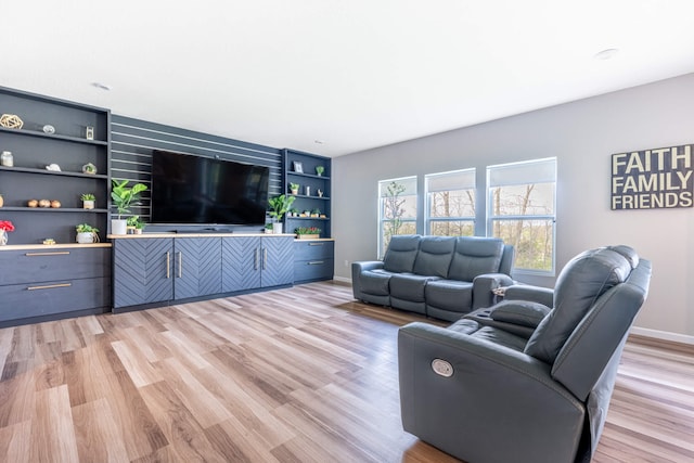 living room featuring baseboards, light wood-type flooring, and built in features