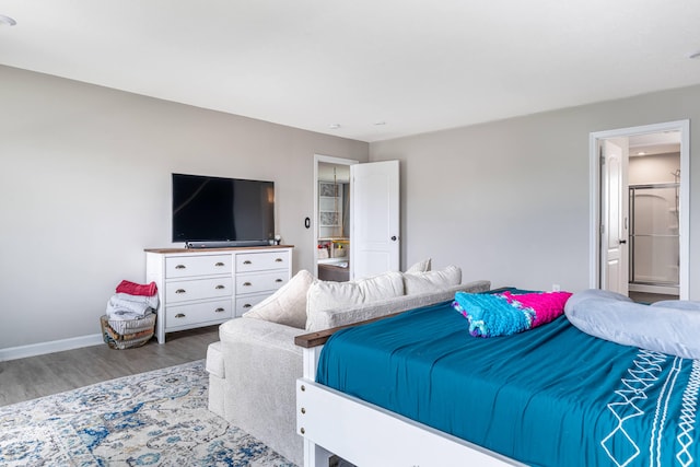 bedroom with baseboards, wood finished floors, and ensuite bath