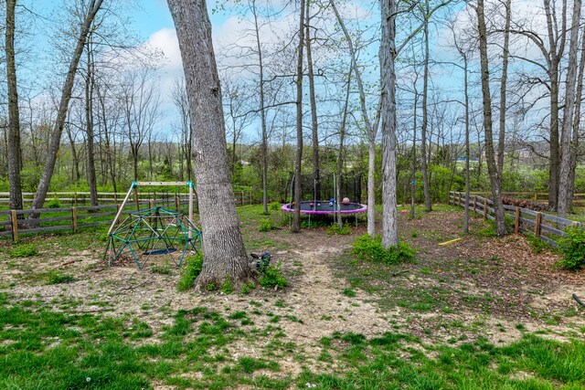 view of yard with fence, a playground, and a trampoline