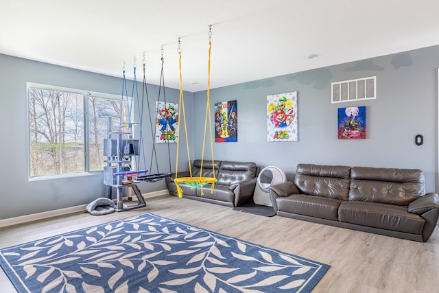 living room featuring baseboards, visible vents, and wood finished floors