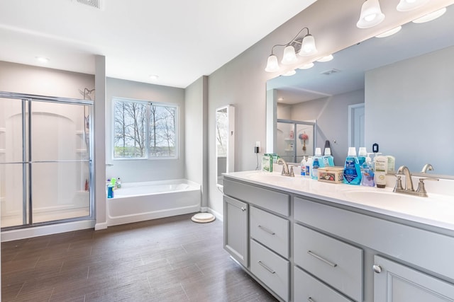 bathroom with a garden tub, a stall shower, double vanity, and a sink