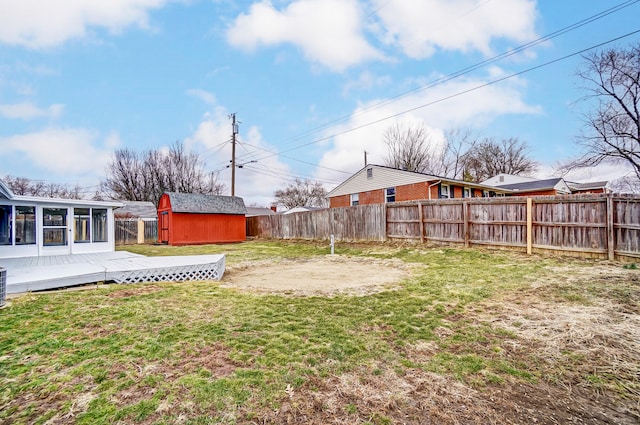 view of yard with a storage shed, a fenced backyard, a wooden deck, and an outbuilding