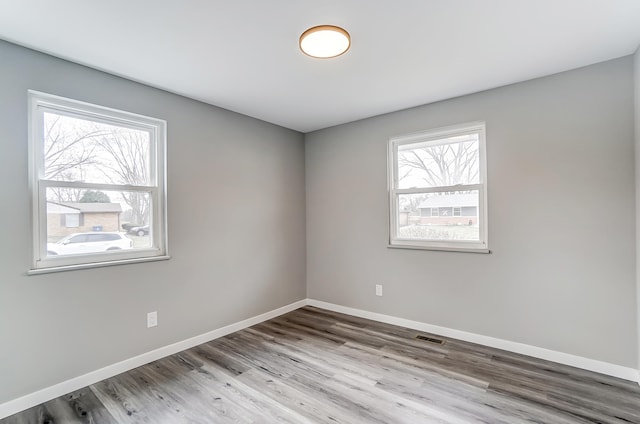 unfurnished room featuring visible vents, baseboards, and wood finished floors