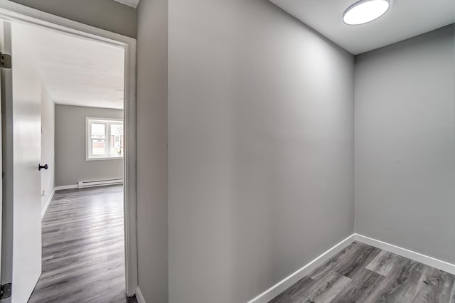 hallway featuring dark wood-type flooring, baseboard heating, and baseboards