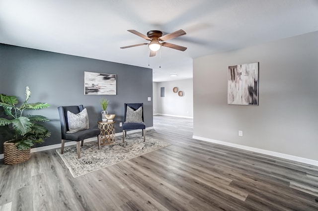 sitting room with a ceiling fan, baseboards, and wood finished floors