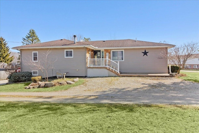 rear view of property featuring a lawn and driveway