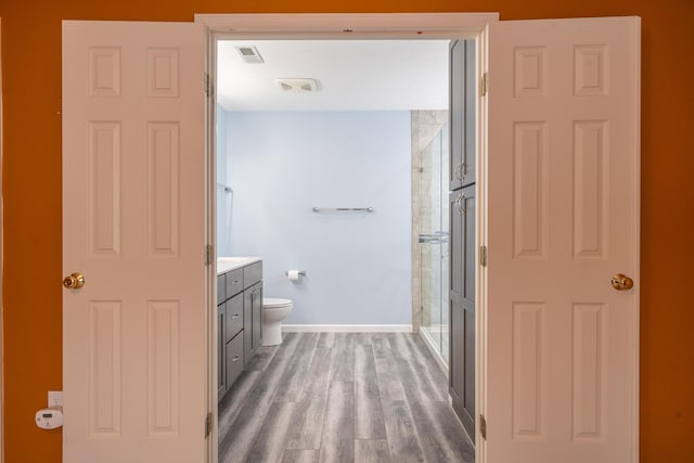 bathroom featuring walk in shower, vanity, toilet, and hardwood / wood-style flooring