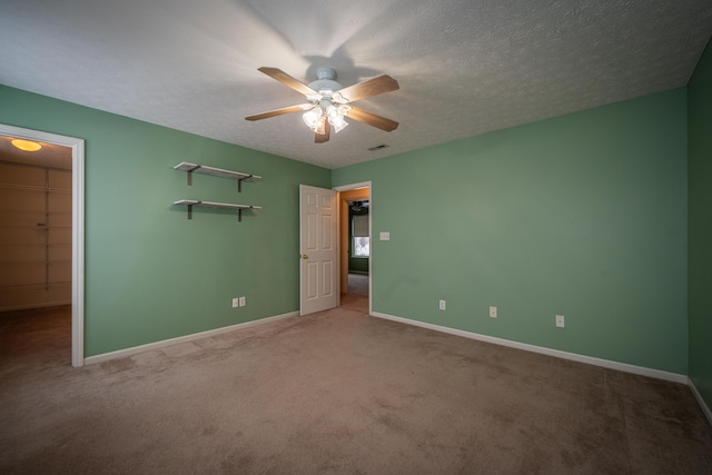 unfurnished bedroom featuring carpet, a spacious closet, ceiling fan, a textured ceiling, and a closet