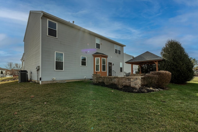 rear view of house featuring a gazebo, a lawn, and central air condition unit