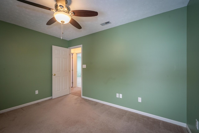 carpeted spare room featuring ceiling fan and a textured ceiling