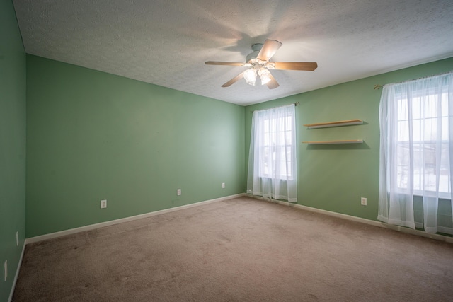 carpeted empty room with ceiling fan, a healthy amount of sunlight, and a textured ceiling