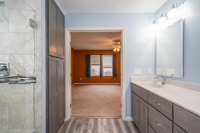 bathroom with a shower with door, vanity, hardwood / wood-style flooring, and ceiling fan