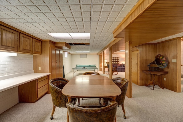 dining area featuring light colored carpet and wood walls