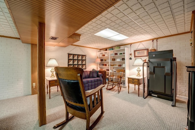 sitting room with light carpet, visible vents, and brick wall