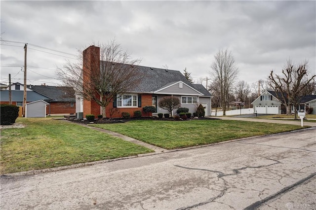 view of front facade with a front lawn, cooling unit, brick siding, and a chimney