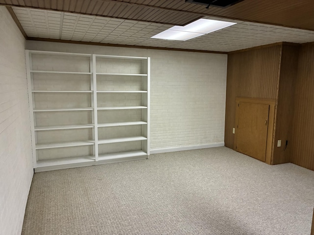 carpeted spare room featuring brick wall and wood walls