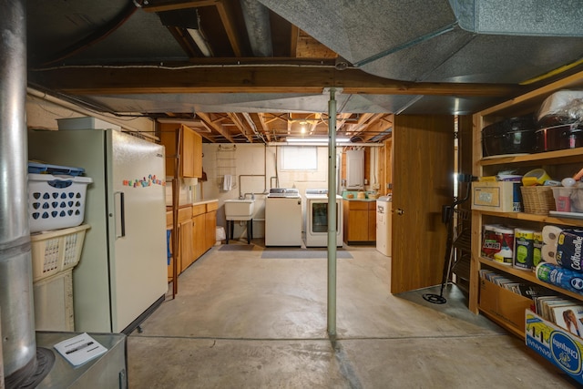 below grade area featuring washer and clothes dryer, freestanding refrigerator, and a sink