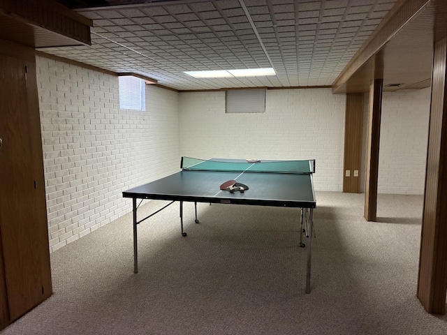 recreation room featuring carpet flooring and brick wall