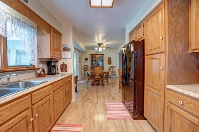 kitchen featuring light countertops, decorative backsplash, light wood-style flooring, freestanding refrigerator, and a sink