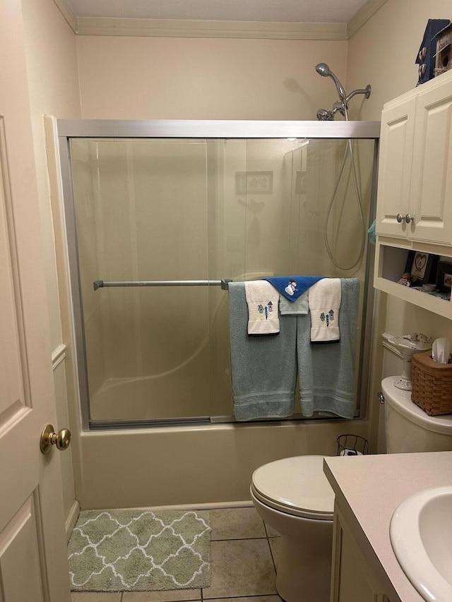 full bathroom featuring bath / shower combo with glass door, vanity, toilet, crown molding, and tile patterned floors